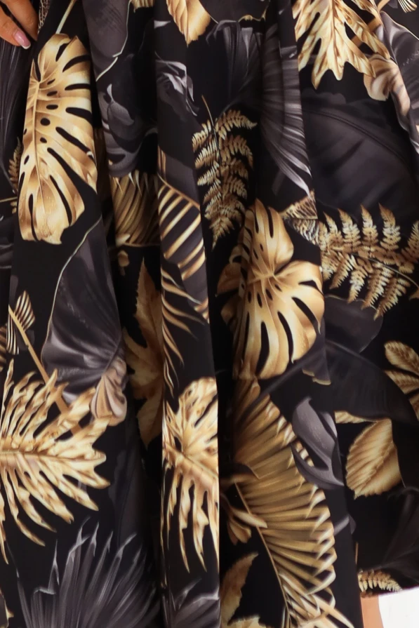 Modelka w czarnej sukience Numoco w złote liście, rozkloszowany fason podkreślający talię