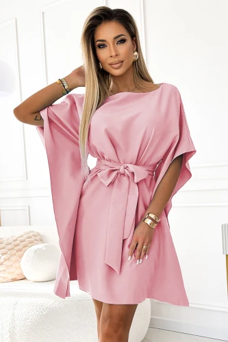 Na zdjęciu widoczna jest kobieca sukienka Sofia w delikatnym różowym kolorze, charakteryzująca się luźnym krojem i ozdobnym paskiem w talii. Sukienka Sofia ma eleganckie, szerokie rękawy, które dodają jej lekkości i stylu.}