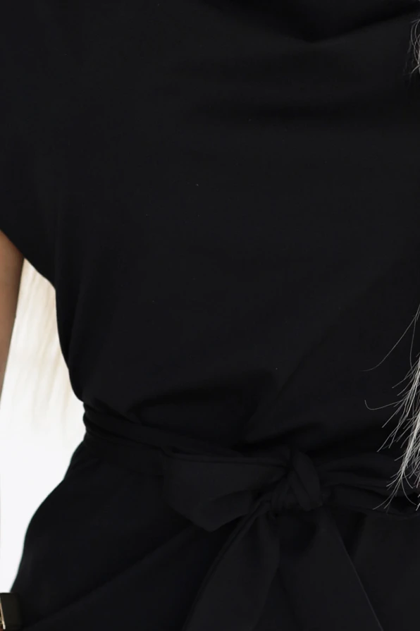 Modelka prezentuje elegancką czarną sukienkę z paskiem w talii od polskiej marki Numoco; klasyczna, dopasowana stylizacja idealna na co dzień i wyjątkowe okazje.