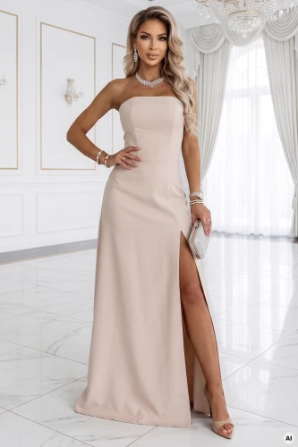 Modelka prezentuje jasnobeżową suknię maxi Numoco bez ramiączek z wysokim rozcięciem, elegancką sukienkę wieczorową w minimalistycznym wnętrzu.}
