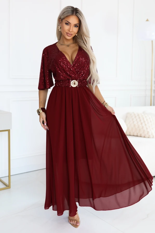 Modelka w bordowej sukience maxi ELVIA marki Numoco Basic z cekinową górą, kopertowym dekoltem, luźnymi rękawami, zwiewnym rozkloszowanym dołem i paskiem z ozdobną klamrą.