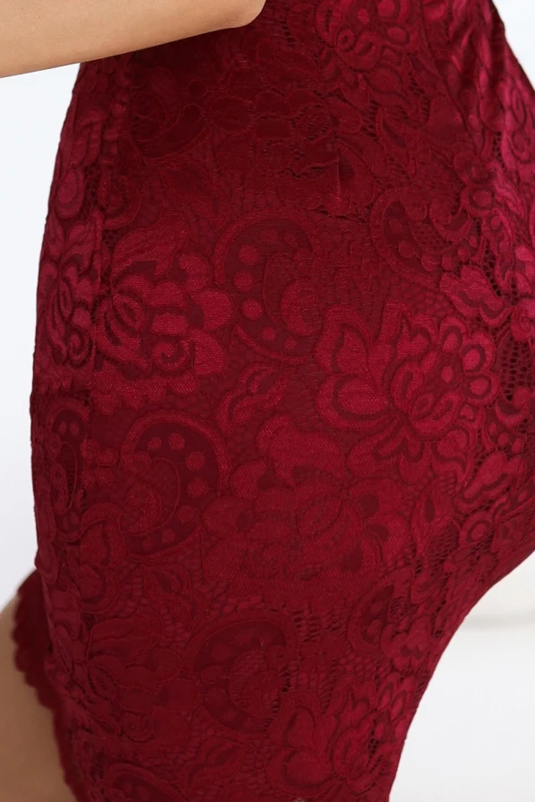 Modelka prezentuje elegancką, koronkową sukienkę ołówkową w kolorze głębokiego bordo, która podkreśla kobiecą sylwetkę i dodaje klasy każdej stylizacji. Jej pewna postawa i delikatny uśmiech idealnie oddają szyk i zmysłowość tej wyjątkowej kreacji marki Numoco.