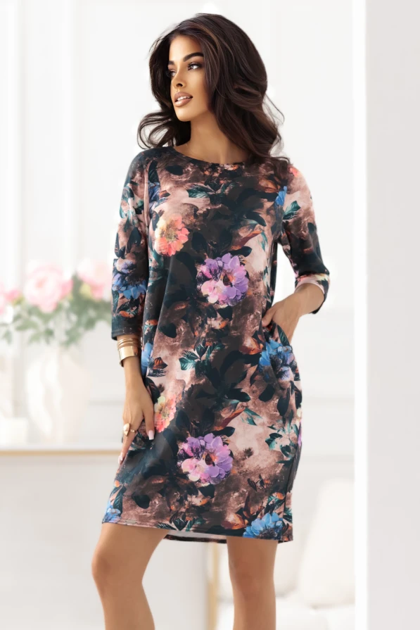 Modelka prezentuje czekoladową sukienkę oversize w kwiaty z kieszeniami marki Numoco, limitowaną edycję polskiej produkcji, idealną na co dzień i wyjątkowe okazje.Modelka prezentuje czekoladową sukienkę oversize w kwiaty z kieszeniami marki Numoco, limitowaną edycję polskiej produkcji, idealną na co