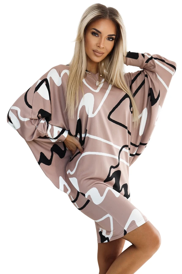 Sweterkowa wygodna sukienka prezentuje się w odcieniach beżu z abstrakcyjnym wzorem w czerni i bieli. Sukienka sweterkowa ma luźny krój z szerokimi rękawami, idealna na codzienne stylizacje.