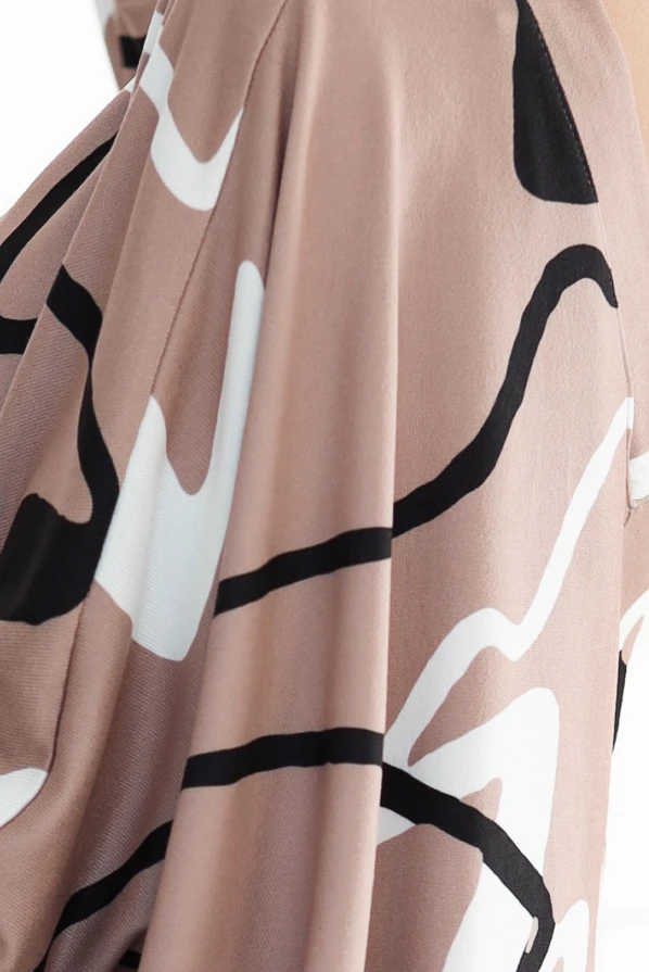 Sweterkowa wygodna sukienka prezentuje się w eleganckim, beżowym kolorze z abstrakcyjnym wzorem w czarne i białe linie. Materiał sukienki jest miękki i zapewnia komfort noszenia, idealny na różne okazje.