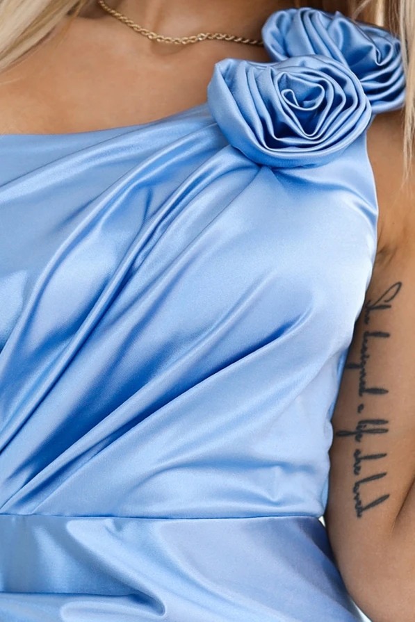 Długa satynowa sukienka Aurora w kolorze niebieskim charakteryzuje się eleganckim drapowaniem i ozdobnymi kwiatami na ramieniu. Sukienka Aurora wykonana z połyskującej satyny idealnie nadaje się na wyjątkowe okazje.