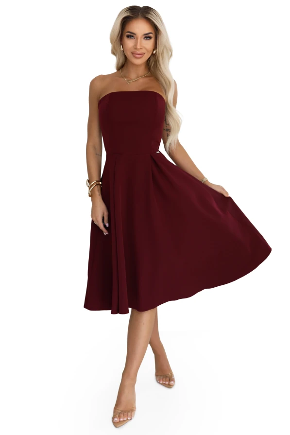 Modelka prezentuje elegancką sukienkę Vivienne midi w kolorze bordowym z rozkloszowanym dołem – stylowa propozycja marki Numoco na wyjątkowe okazje.